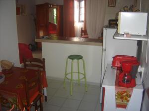 a kitchen with a counter and a table and a stool at Chez L'habitant in Capesterre-Belle-Eau