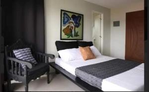 a bedroom with a bed and a black chair at SanRosa Boutique Hotel BnB in Bulalakao