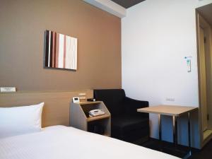 a bedroom with a bed and a chair and a table at Hotel Route Inn Ono in Ono