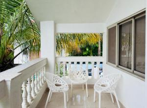 a porch with white chairs and a table and windows at Spellbound in Wadgaon