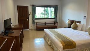 a bedroom with a bed and a desk and a television at Baan Pitcha บ้านพิชชา in Lamai