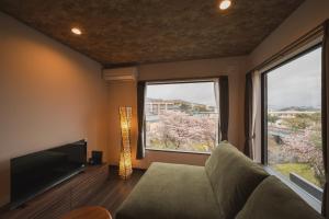 a living room with a couch and a tv and two windows at みたまの湯宿 in Beppu