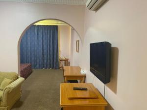 a living room with a couch and a tv on a wall at Hotel Al Masa in Al Buraymī