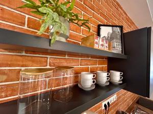 a kitchen counter with cups and plates and a brick wall at BT Apartman in Miercurea-Ciuc