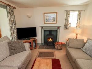 a living room with a fireplace and a tv at Rose Cottage Coniston in Coniston