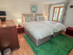 a bedroom with two beds and a table and a window at Rose Cottage Coniston in Coniston