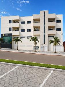 a white building with palm trees in front of it at Apt Aconchegante no Centro de Rolim in Rolim de Moura