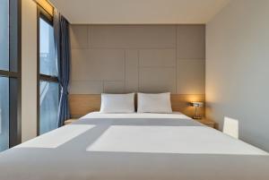 ein Schlafzimmer mit einem großen weißen Bett und einem Fenster in der Unterkunft Hotel POCO Seongsu in Seoul