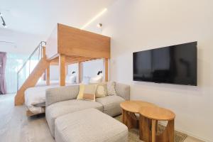a living room with a couch and a tv on a wall at Cavatina in Sapporo