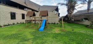 a playground in front of a house with a blue slide at Blu light lodge in Randfontein