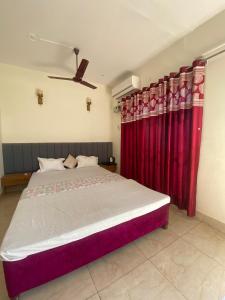 a bedroom with a large bed with red curtains at Sanskriti in Kotdwāra