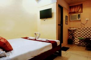 a bedroom with a bed with a tv and a bathroom at Hotel Amrapali Bhiwandi in Bhiwandi