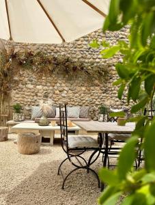 a table and chairs in front of a stone wall at La Suite Drômoise 1809 in Saint-Paul-lès-Romans