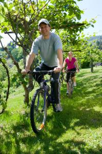 Ein Mann und eine Frau fahren Fahrrad in einem Park in der Unterkunft Energy Hotel in Calceranica al Lago