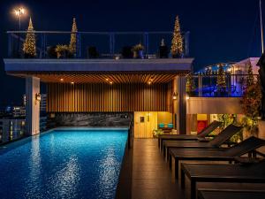 a swimming pool on top of a building at night at The Elysium Prațumnak Pattaya - By SHG in Pattaya South