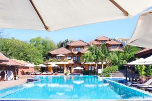 a pool at a resort with chairs and umbrellas at Poshanu Boutique Resort in Mui Ne