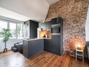 a kitchen with black cabinets and a brick wall at Two-bedroom apartment by the river in Antwerp