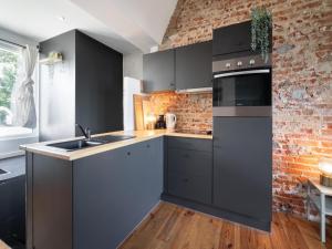 a kitchen with black cabinets and a brick wall at Two-bedroom apartment by the river in Antwerp