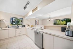 a large kitchen with white counter tops and windows at Fairway Retreat in The Vines