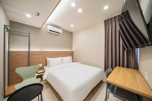 a hotel room with a white bed and a desk at Calm Rest Hotel Masan in Changwon