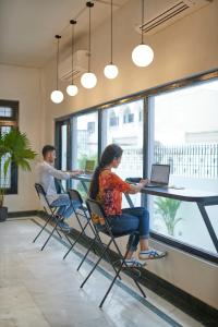 a man and a woman sitting at a table with a laptop at Poshtel VNS in Varanasi
