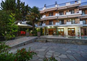 a hotel with a stone patio in front of a building at Syrtaki Hotel in Ofrínion