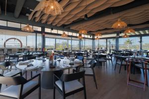 a dining room with tables and chairs and windows at Villa Don Grosa - Luxury Family Retreat in Torre-Pacheco