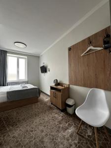 a hotel room with a bed and a white chair at Asmanguesthouse in Naryn