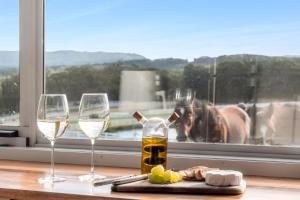 a table with two wine glasses and a horse in a window at Bilpin Station in Bilpin