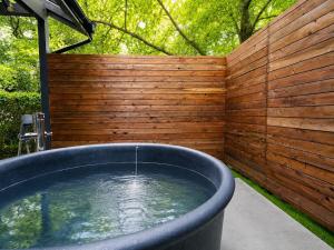 a large tub with water in front of a wooden fence at rinne 伊豆 Private Spa in Ito