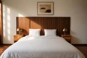 a bedroom with a large white bed with two lamps at Residencial Rochili in Chimoio