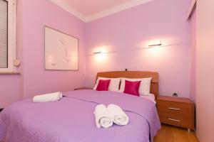 a purple bedroom with a bed with towels on it at Apartment Arcadia in Rijeka