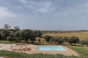 a swimming pool in a field with chairs around it at Vagar do Pastor in Alandroal