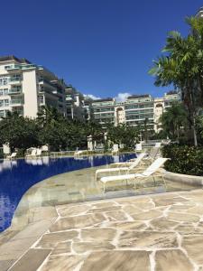 uma piscina com cadeiras e edifícios ao fundo em Le Parc Residential Resort no Rio de Janeiro