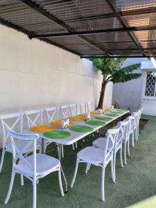 a long table with white chairs and a green table at Hotel Urban Home in Guatemala