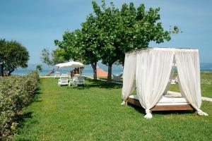 a bed in a field with chairs and umbrellas at Melador beachfront studios in Kavos
