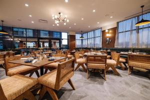 a restaurant with wooden tables and chairs and windows at The Hotel Rambler Montgomery, Tapestry Collection By Hilton in Montgomery