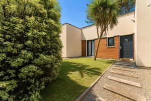 a house with a palm tree next to a building at Le Reve Mimizan Plage in Mimizan-Plage