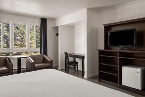 a hotel room with a bed and a flat screen tv at Ramada by Wyndham Laval in Laval