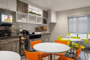 a restaurant with white tables and orange chairs at Ramada by Wyndham Laval in Laval