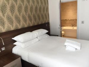 a bedroom with a bed with white pillows and a bathroom at Marlborough Hotel in Liverpool