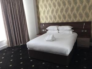 a hotel room with a bed with white sheets and pillows at Marlborough Hotel in Liverpool