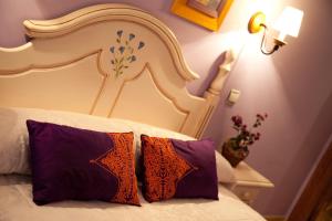 Schlafzimmer mit einem Bett mit lila und orangefarbenen Kissen in der Unterkunft Las Anjanas de Isla in Isla