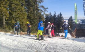 a group of people skiing down a snow covered slope at Domek MIŚ Na Stoku in Tylicz