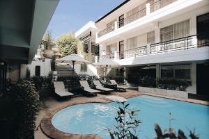 a swimming pool with chairs and umbrellas next to a building at Fullrich Lanna Suite in Chiang Mai