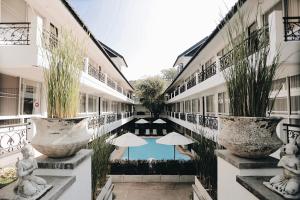 a courtyard of a building with a pool and umbrellas at Fullrich Lanna Suite in Chiang Mai