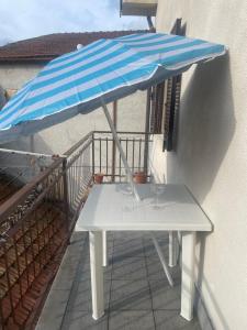 a table with a blue and white umbrella on a balcony at Casa nonna Bruna in Montebruno