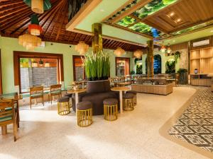 a restaurant with tables and chairs and a plant at Puri Sading Hotel in Sanur