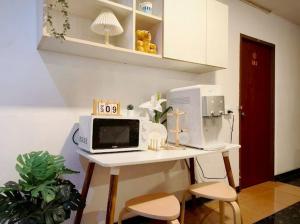a white desk with a microwave and two chairs at Xin Hotel at Udomsuk 25 in Bangna