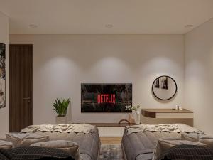 ein Wohnzimmer mit zwei Betten und einem Fernseher an der Wand in der Unterkunft Halora Ten Lua Hotel in Ho-Chi-Minh-Stadt